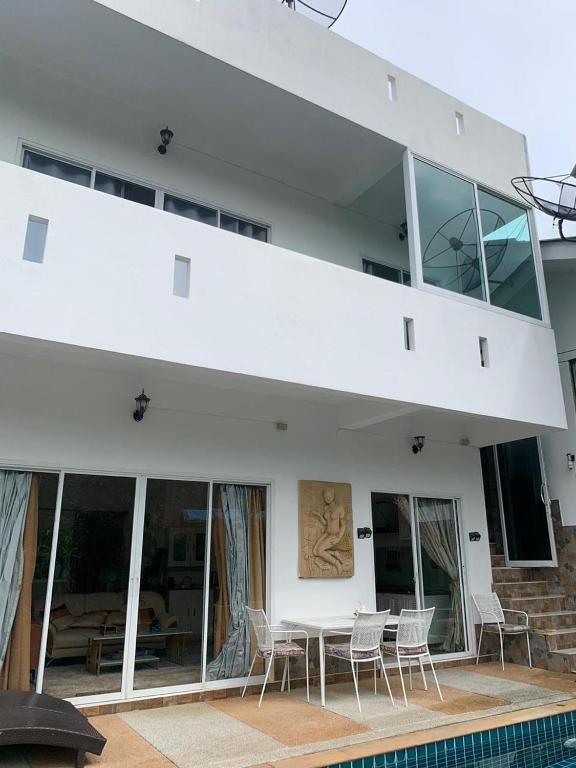 a white house with a table and chairs at Studio du Bonheur Mer et Nature Rawai beach in Nai Harn Beach