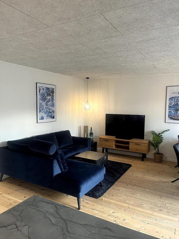 a living room with a blue couch and a tv at 3 værelses lejlighed in Herning