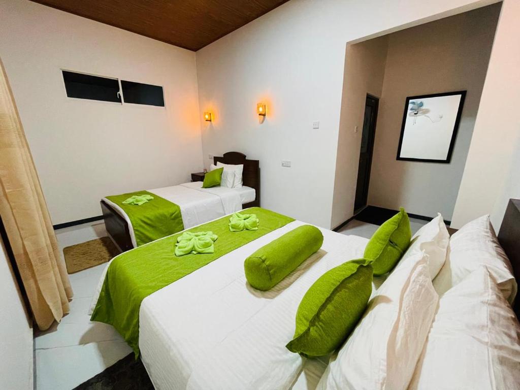 two beds in a room with green and white at Erene Inn in Ella