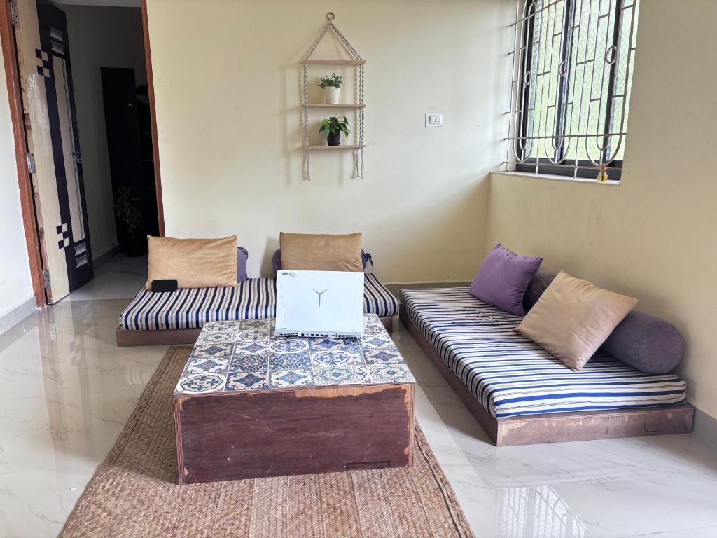 a living room with two couches and a laptop on a table at South Goa homestay near Rajbag Beach in Canacona
