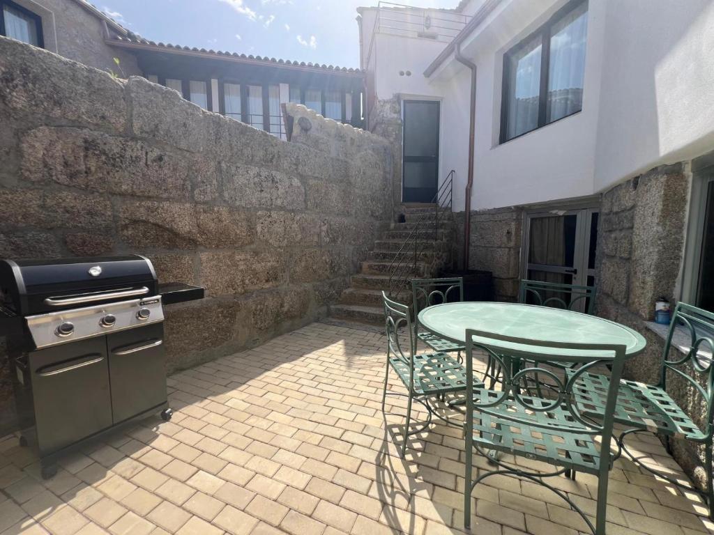 a patio with a grill and a table and chairs at YourHouse O Canton 3 in Lobios