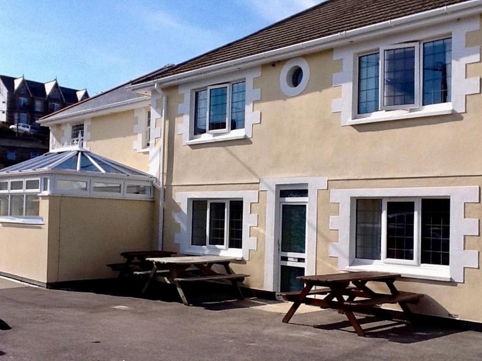 ein Haus mit zwei Picknicktischen davor in der Unterkunft Pirans Apartments in Perranporth