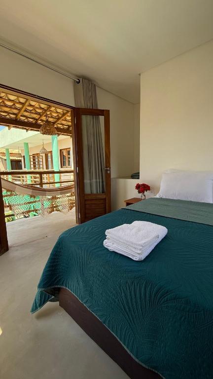 a bedroom with a bed with a green blanket at Chalé Sol Nascente Milagres in São Miguel dos Milagres