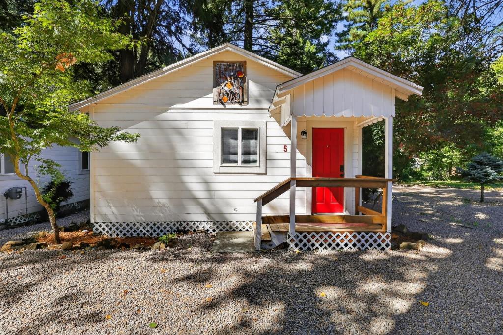 una pequeña casa blanca con una puerta roja en Cobb Mountain Nature Escape cabin, en Cobb