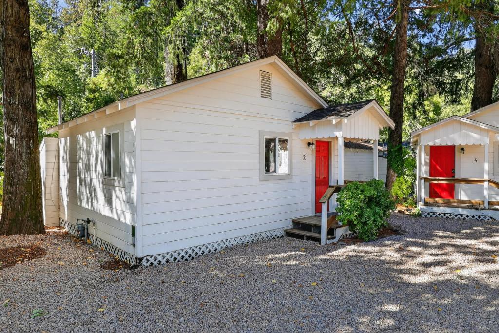 a white house with a red door and trees at Dog-Friendly Cabin 2 Mi to Trails cabin in Cobb