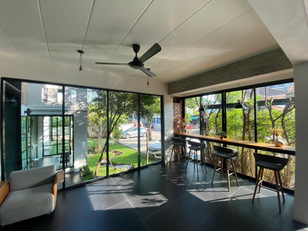 A glass-walled common room combines a sofa, bar-height counter seating and a ceiling fan.