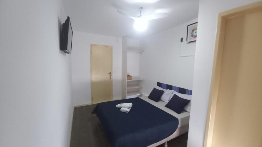 a bedroom with a bed with blue sheets and pillows at Quartos Suítes Pousada, 4 min da Praia in Salvador