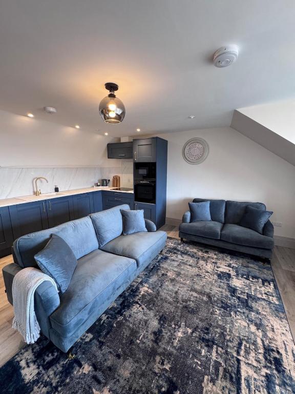 a living room with a blue couch and a kitchen at Abhaille Chluaidh - Macaulay Letting in Helensburgh
