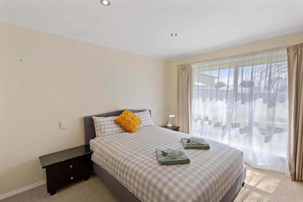 Un dormitorio con una cama y una ventana grande. en Comfortable 4-Bedroom Home with Backyard Escape, en Mount Gambier