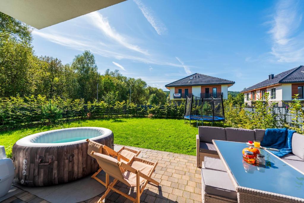 a patio with a table and chairs and a hot tub at Apartament rodzinny Słoneczna Sosnówka in Sosnówka