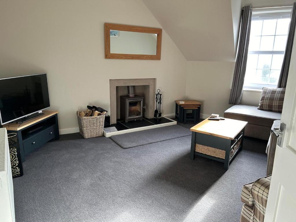 Una sala de estar con televisión y chimenea. en The Attic Portpatrick, en Portpatrick