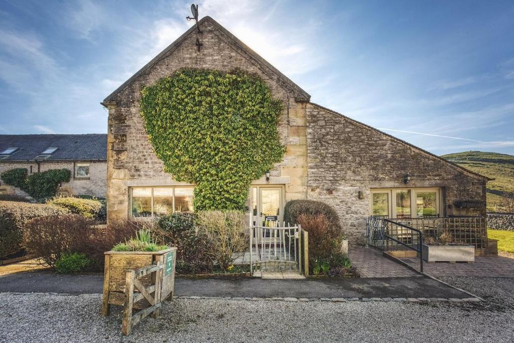 ein Backsteingebäude mit grünem Efeu darauf in der Unterkunft Priestley Cottage in Buxton