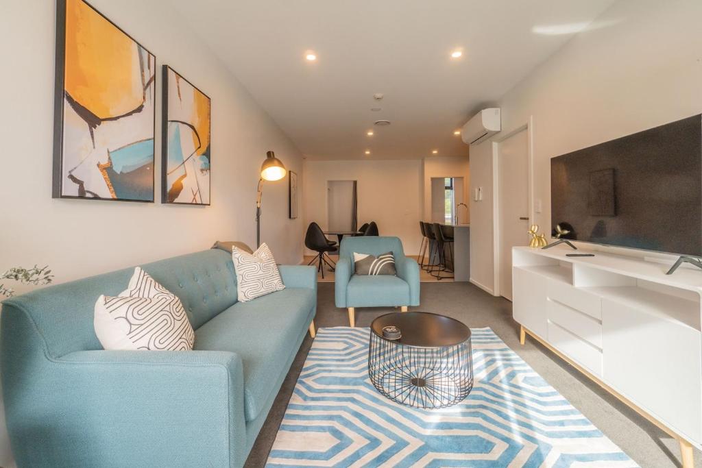 a living room with a blue couch and a sink at High End Centrally located apartment with carpark in Auckland