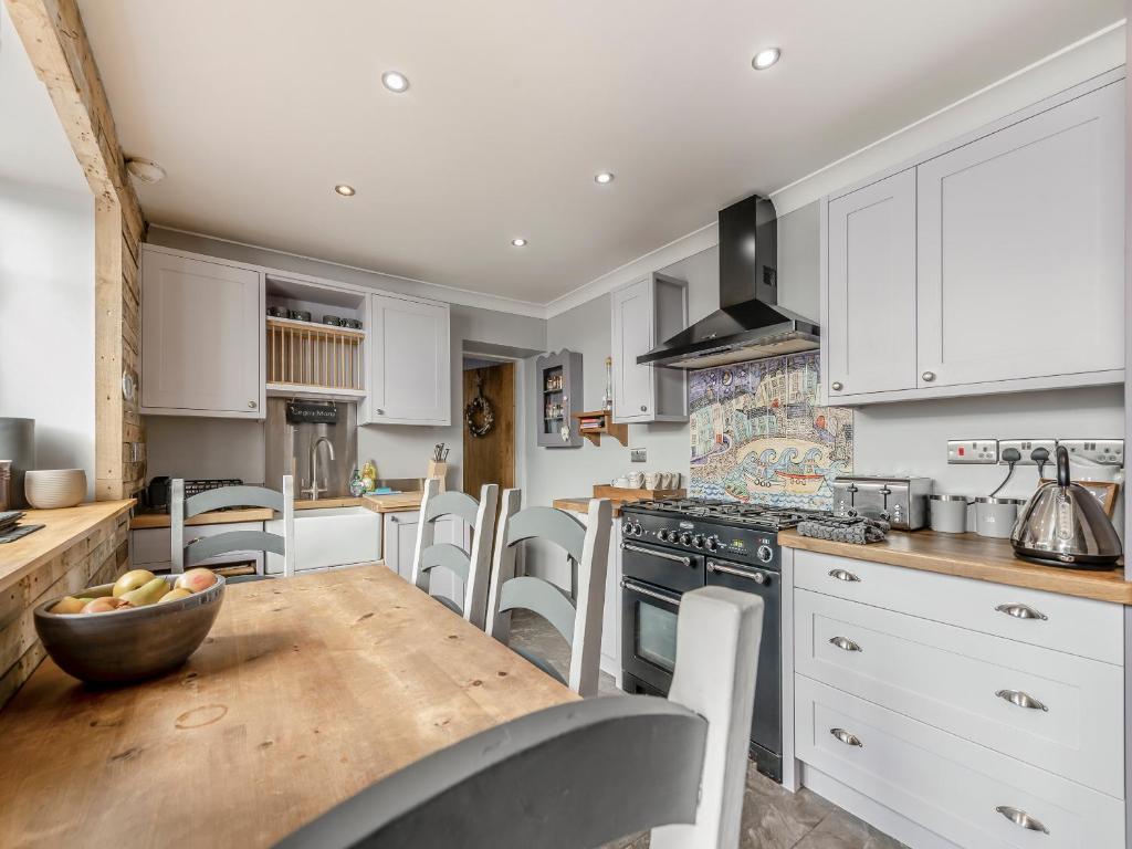 a kitchen with white cabinets and a wooden table at Nelson Cottage in Tenby