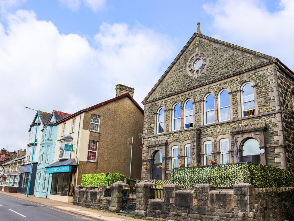an old stone building with a clock tower on a street at The Auction House in Criccieth