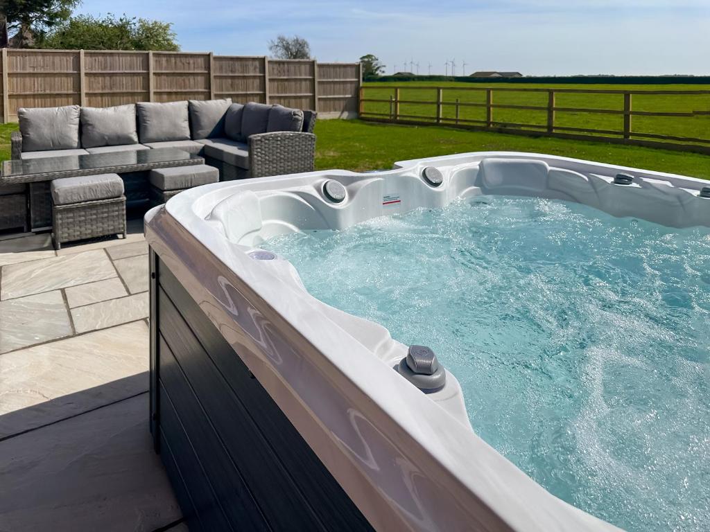 a large hot tub in a backyard with a patio at Cowslip Cottage - Uk47072 in Maltby le Marsh