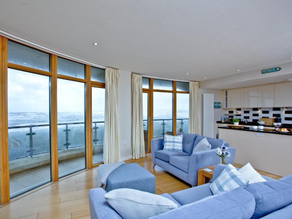 sala de estar con muebles azules y ventanas grandes. en Pebbles, Horizon View, en Westward Ho