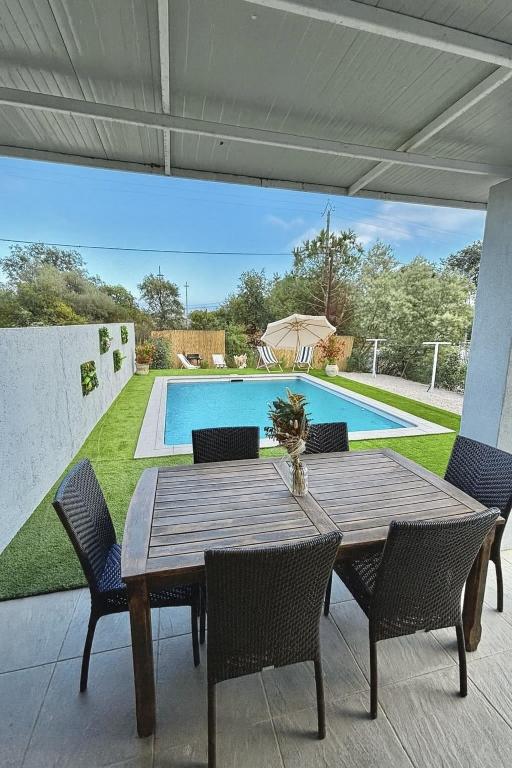 a wooden table with chairs and a swimming pool at Maison Dolce Vita in Ghisonaccia