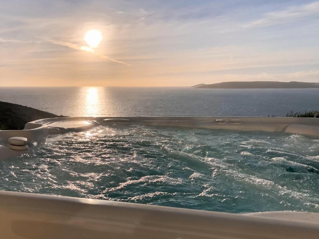 a bath tub with the ocean in the background at Crownhill Bay Garden Suite - Uk47511 in Turnchapel