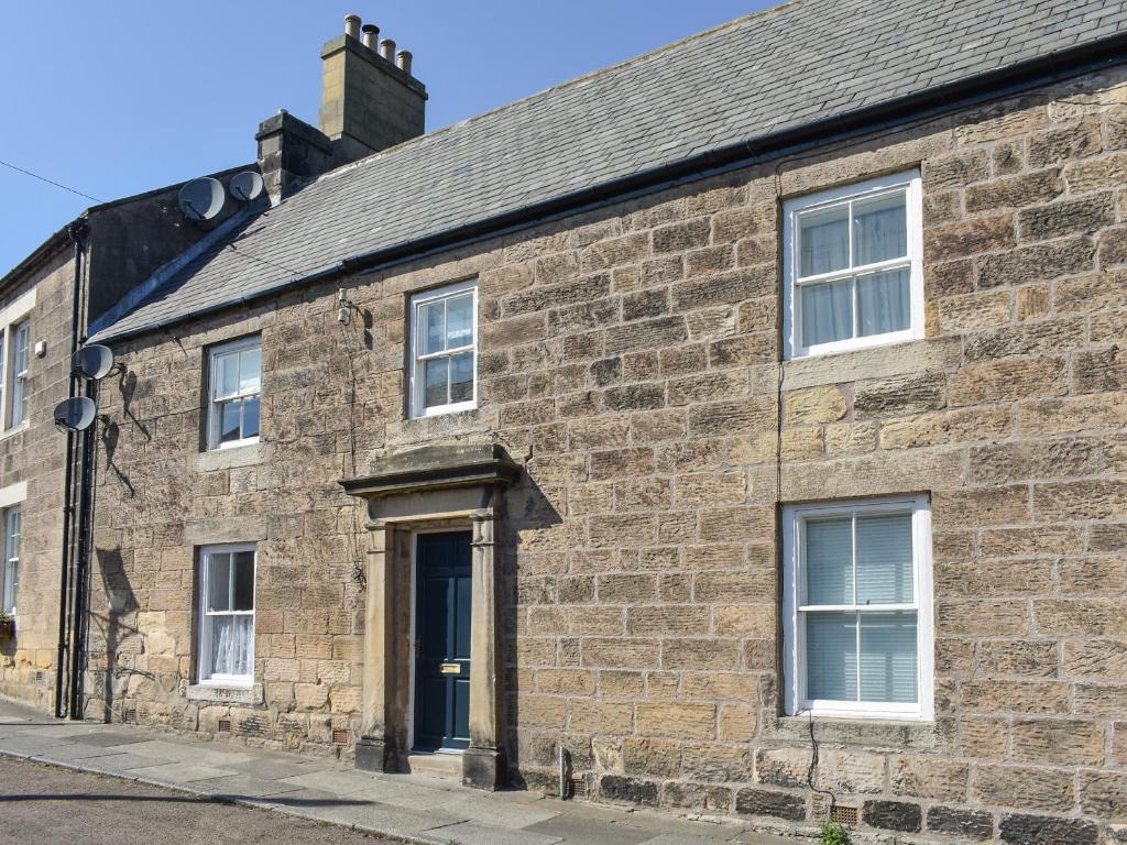 an old brick building with a blue door at The Cottage Highfield in Rothbury