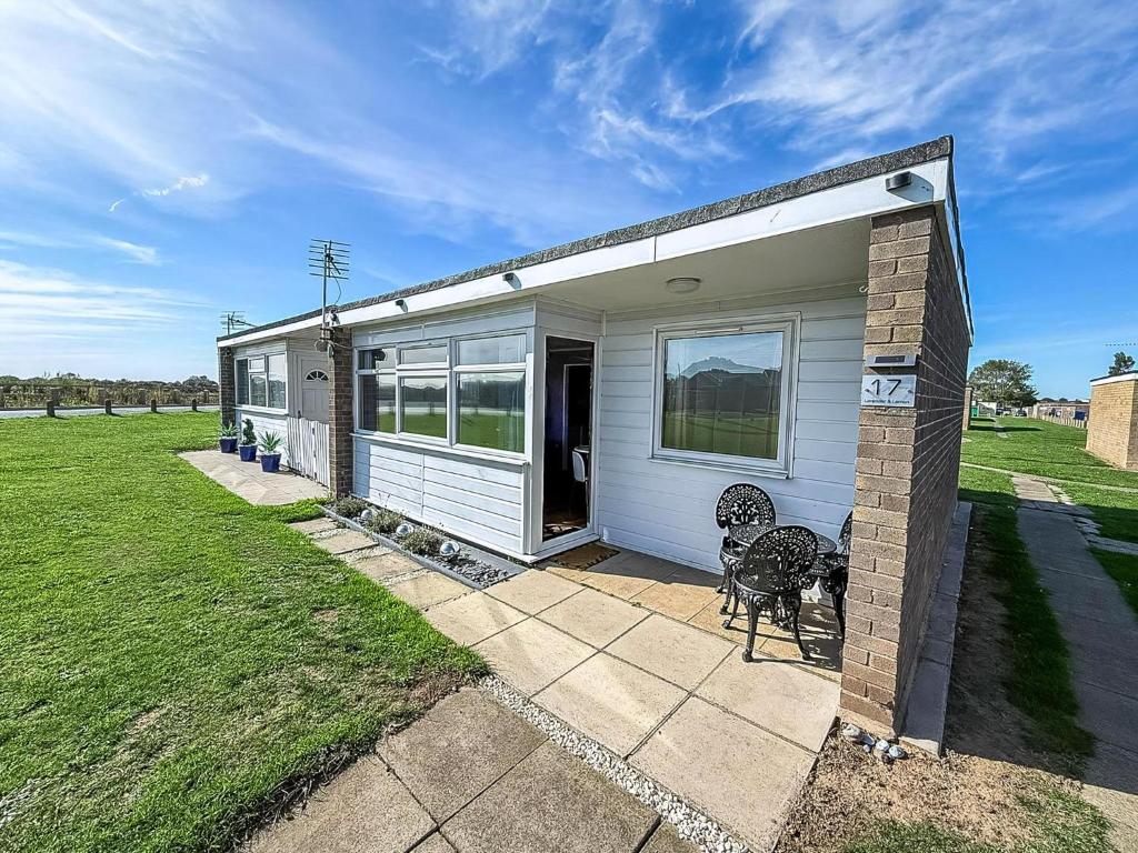 a small white house with a bench in a yard at Stunning Chalet In The Charming Seaside Village Of Scratby, Norfolk Ref 51017S in Great Yarmouth