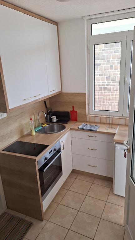 Una cocina con gabinetes blancos y un fregadero y una ventana. en Studio Jupi, en Pržno