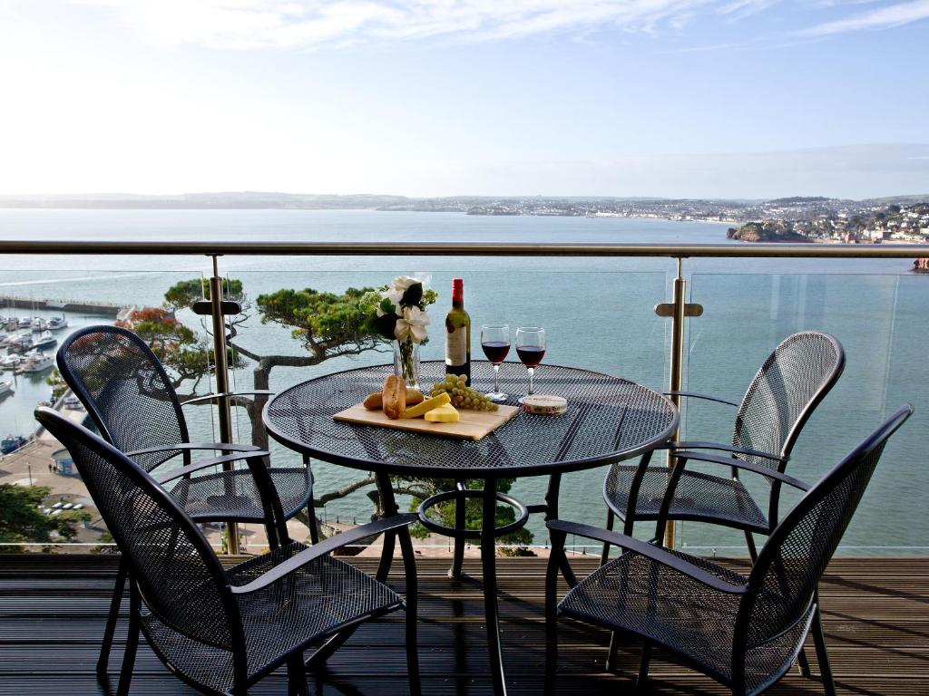 a table with two glasses of wine on a balcony at Harbreck Heights -Masts B9 in Torquay
