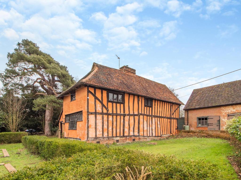an old house in a field next to a building at The Cottage in East Bergholt
