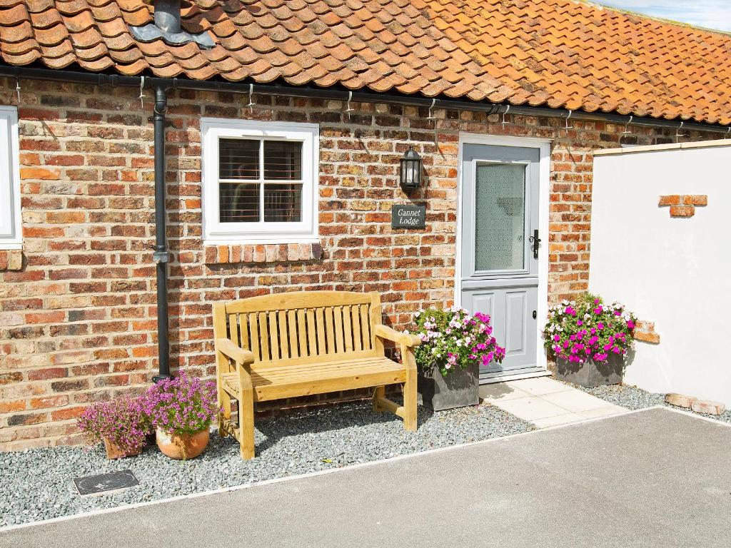 a wooden bench sitting outside of a brick house at Gannet Lodge - Uk30977 in Bempton