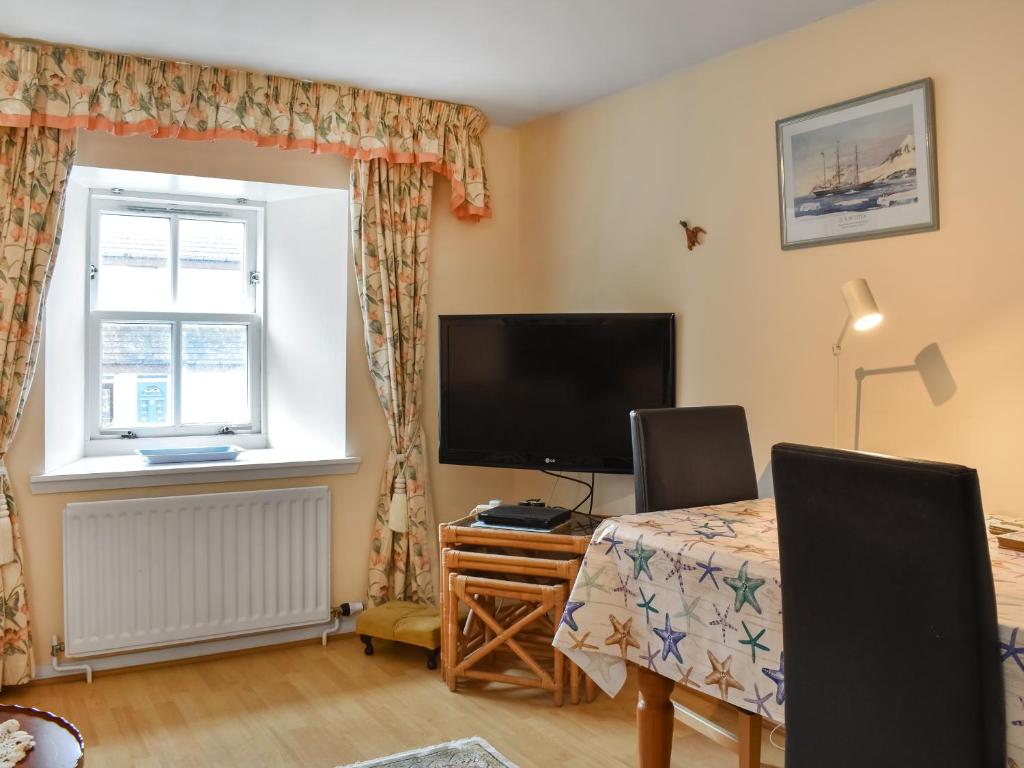 a room with a tv and a table and a window at Cowie Mill Apartment in Stonehaven