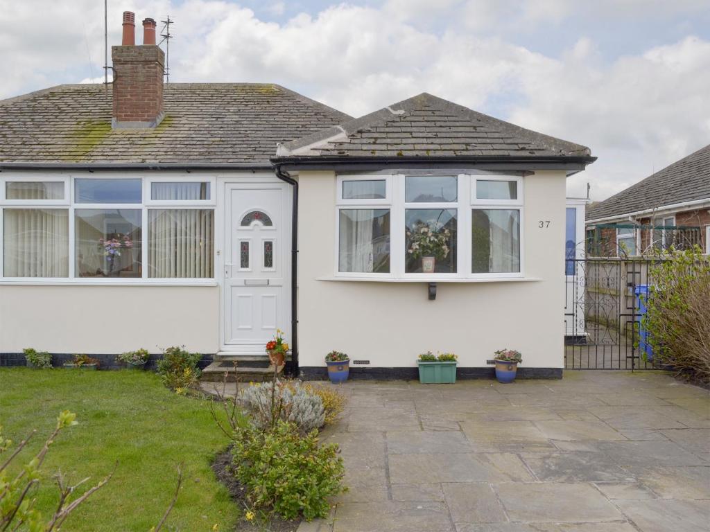 a white house with large windows and a yard at Rossall Beach Cottage in Cleveleys