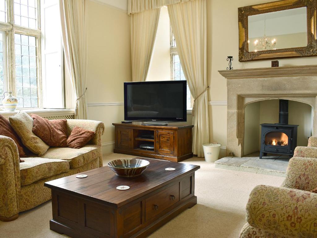 sala de estar con TV y chimenea en The Farmhouse, en Holwell