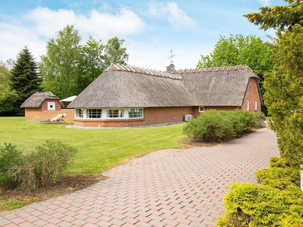 a large brick house with a roof on a field at 12 person holiday home in Væggerløse in Marielyst