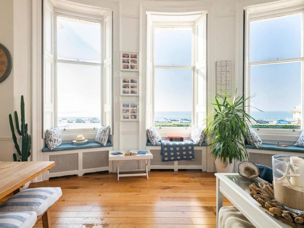 a living room with windows and a view of the ocean at The Little Beach House in Brighton & Hove