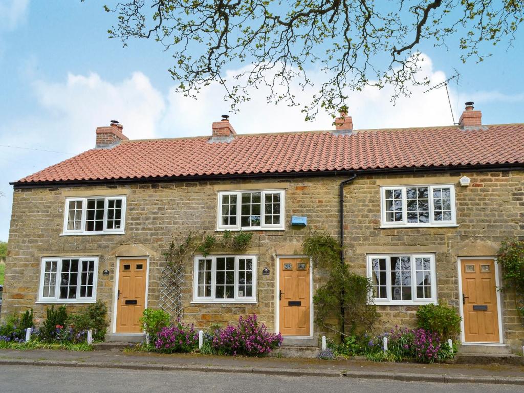 a brick house with brown doors and flowers at Keldholme Cottages 2 - Uk11488 in Kirkbymoorside