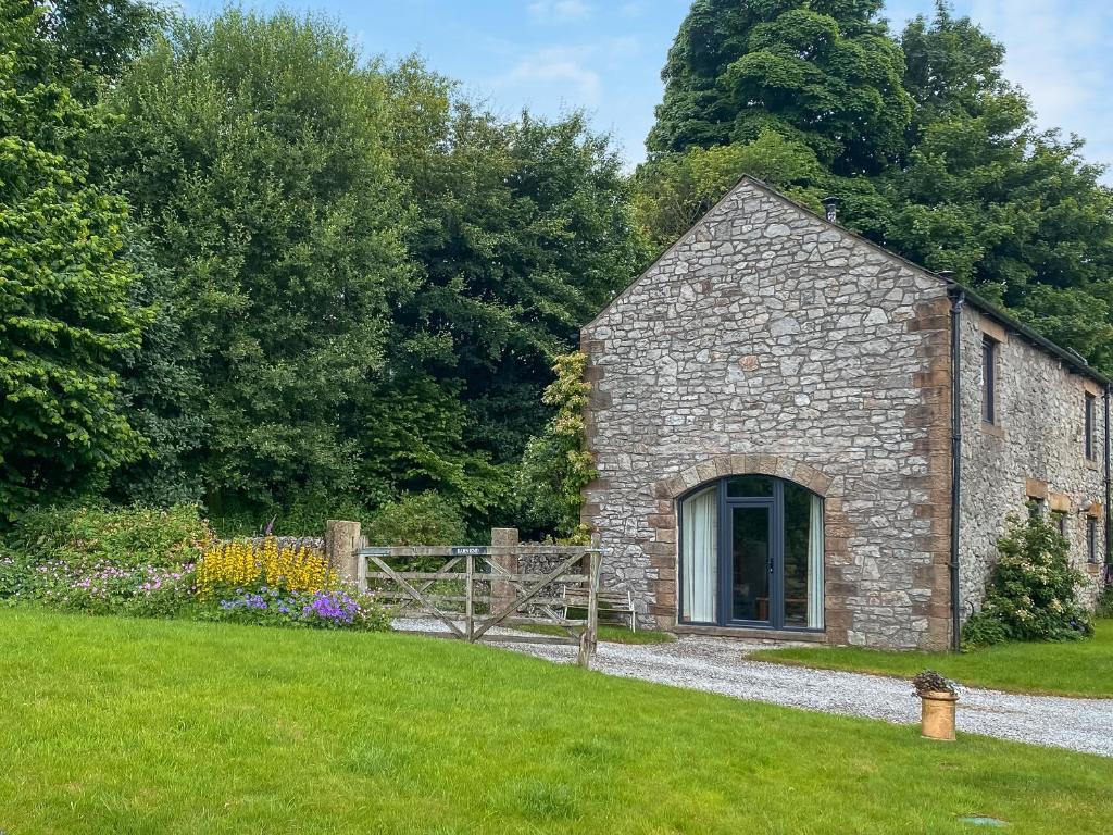 an old stone building with a gate in a yard at Barn End Cottage in Millers Dale