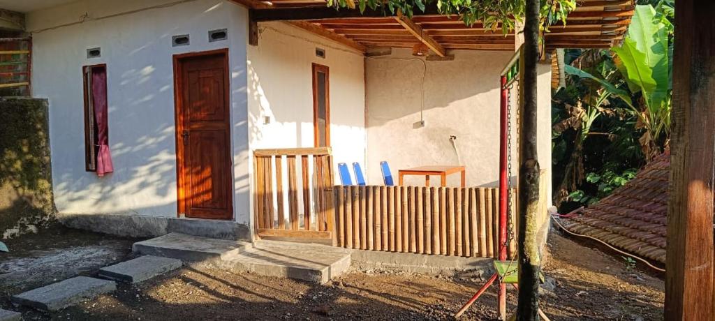 a small white house with a wooden door and a table at Tetebatu Terrace Hostel in Tetebatu