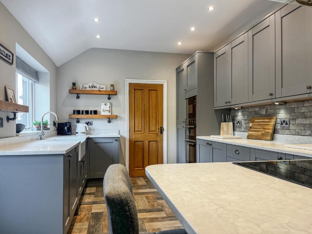 a kitchen with white cabinets and a wooden door at Cracken Cottage - Uk48297 in Chinley