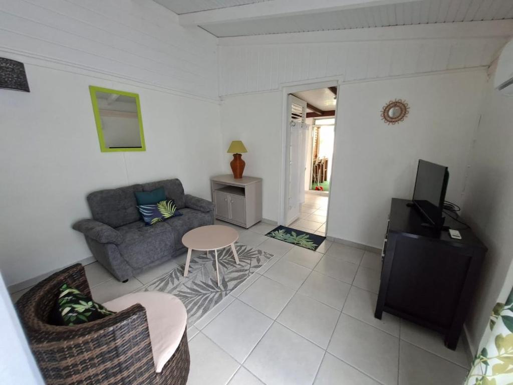 a living room with a couch and a table at Charmant F2 créole in Sainte-Luce