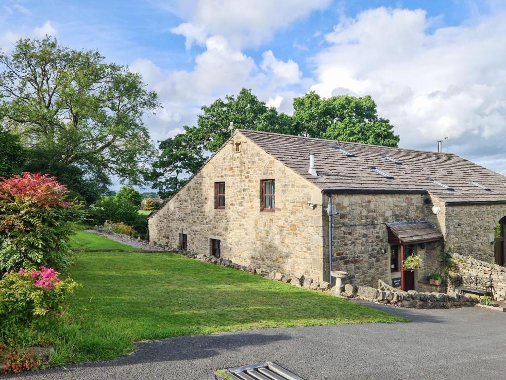 un vecchio fienile in pietra con un prato di Hollin Bank Cottage a Salterforth