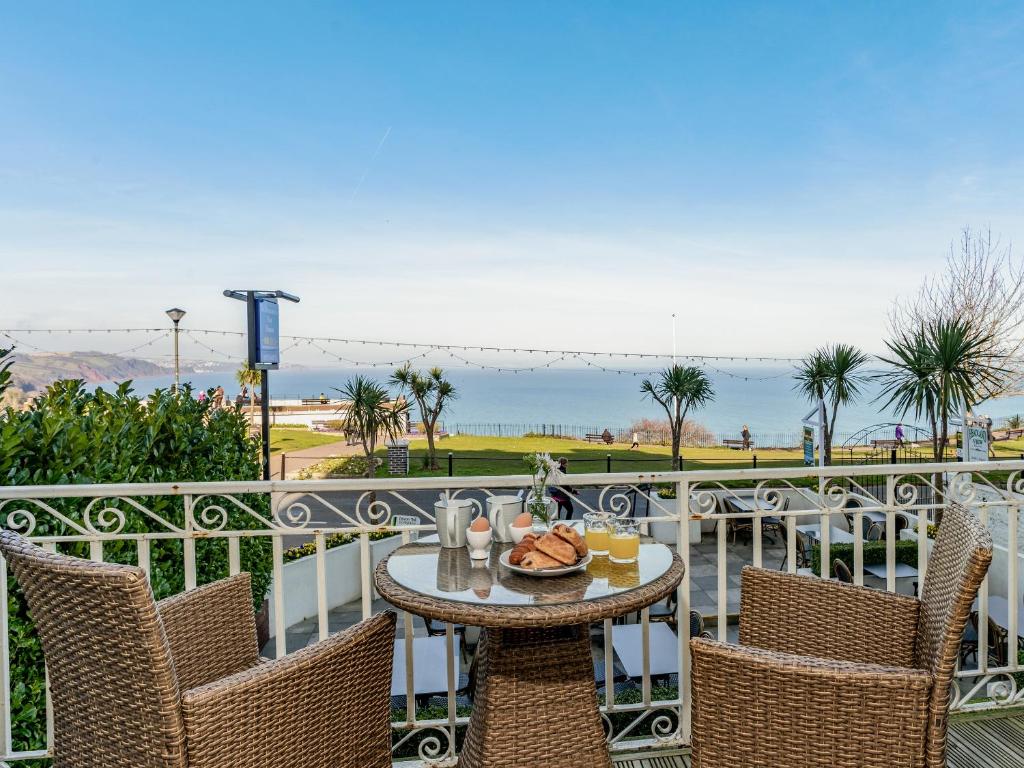 a table and chairs on a balcony with a view of the ocean at The Downs in Torquay