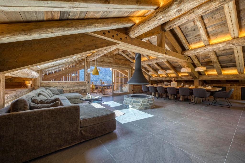 Una sala de estar con techos de madera y un sofá y sillas. en La Ferme, en Le Fernuy