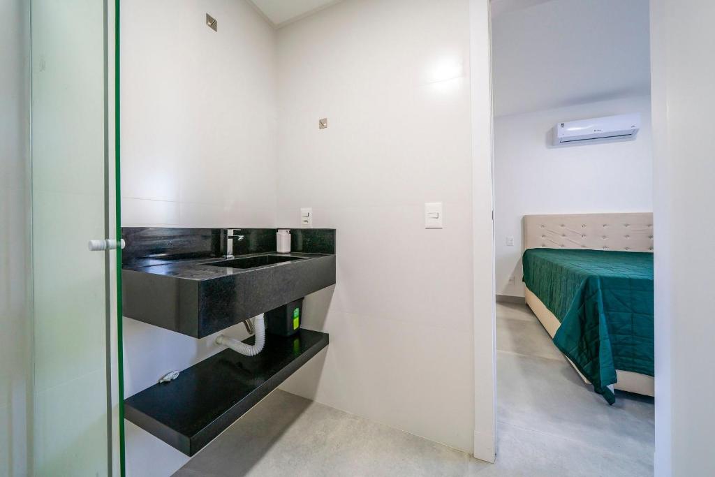 a bathroom with a sink and a bed in a room at Solar do Atlântico 214 in Bombas