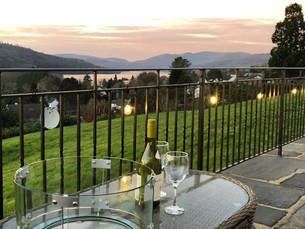 a glass table with a bottle of wine and two glasses at Hazelrigg in Bowness-on-Windermere