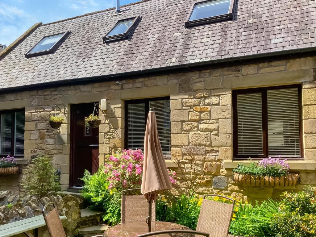 an old stone house with an umbrella in front of it at The Old Forge in Alnwick