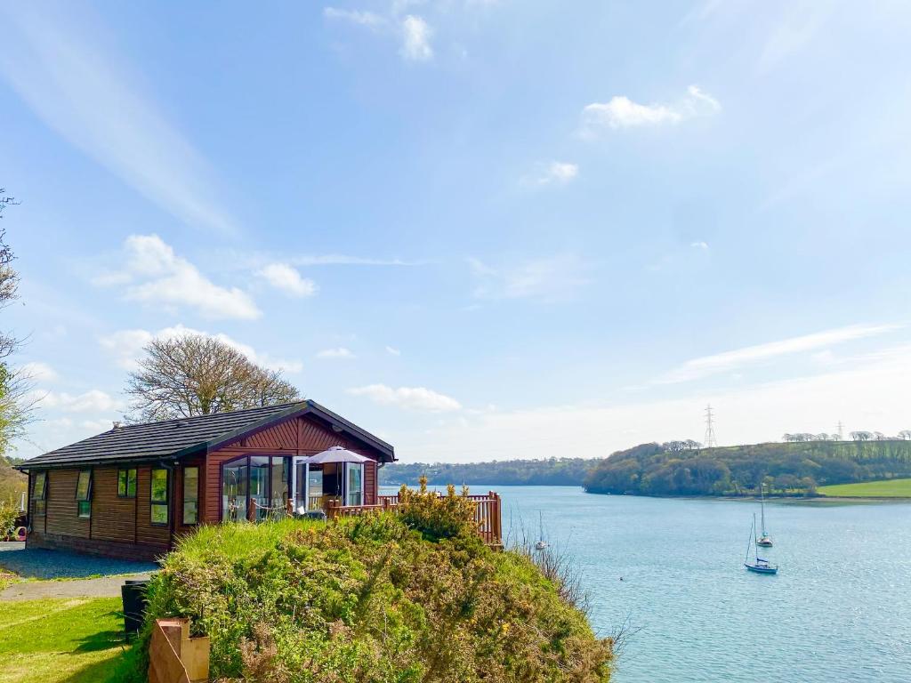 a small house on a hill next to a lake at Badger Lodge in Burton