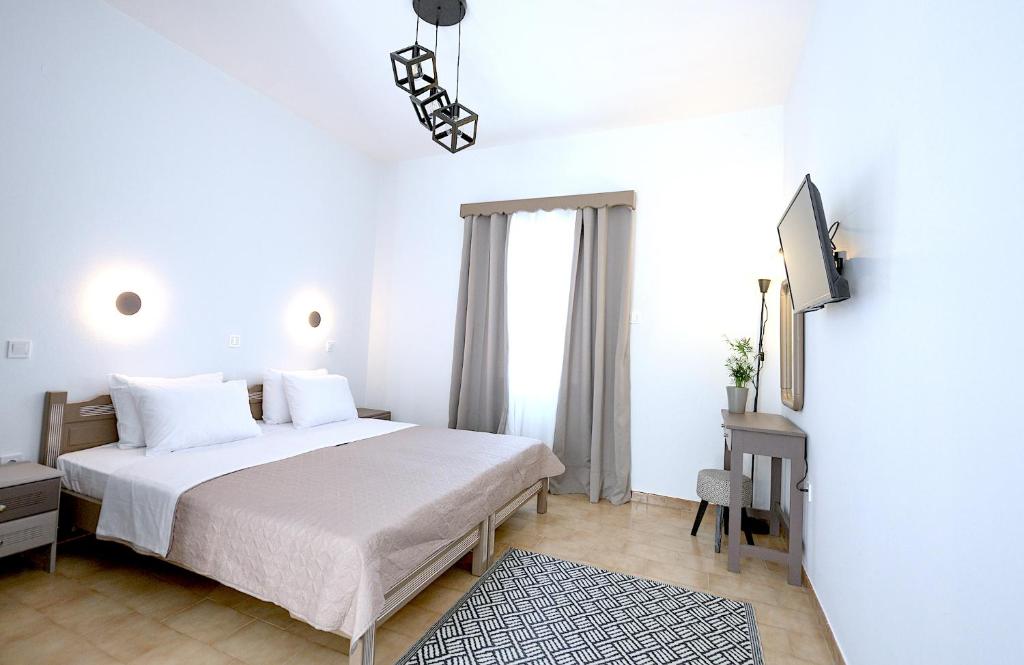 Un dormitorio blanco con una cama y un televisor. en Verano Studios, 