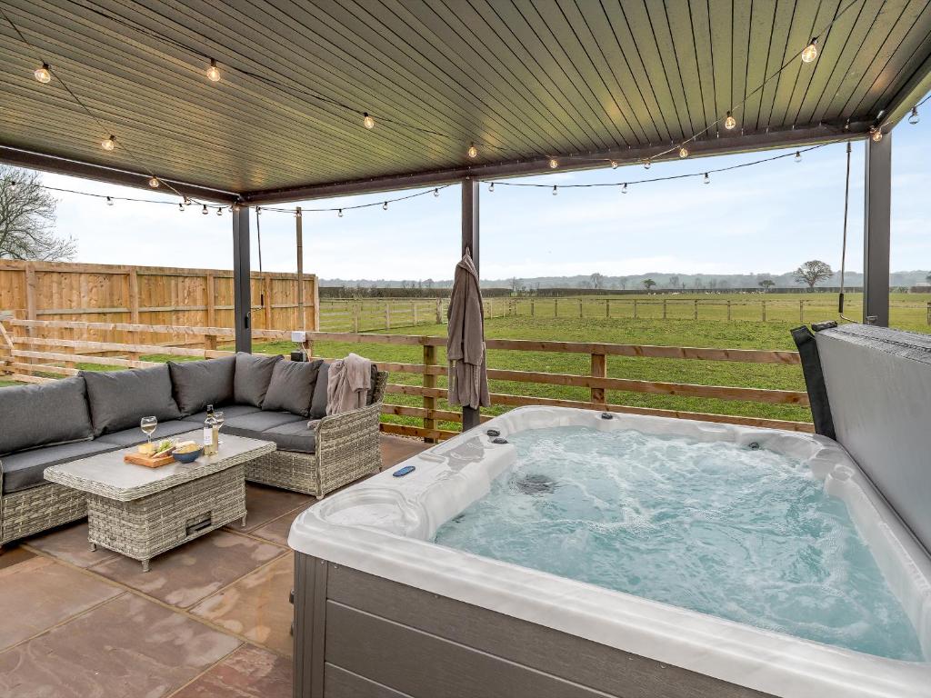 a jacuzzi tub on a patio with a fence at The Workshop - Uk42470 in Middleton