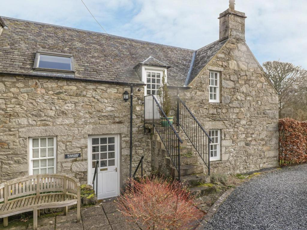 - un ancien cottage en pierre avec un banc devant dans l'établissement Weavers Cottage, à Kenmore