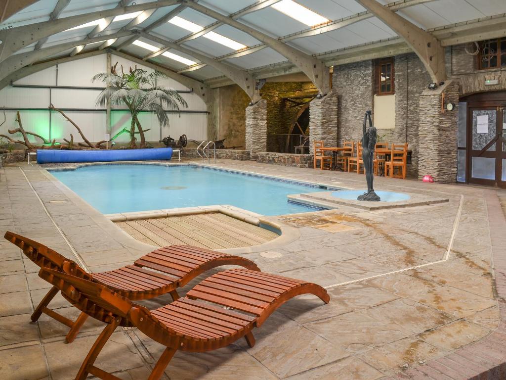 einen Pool mit zwei Stühlen und einer Bank in der Unterkunft Manor Cottage -Ukc3782 in West Down